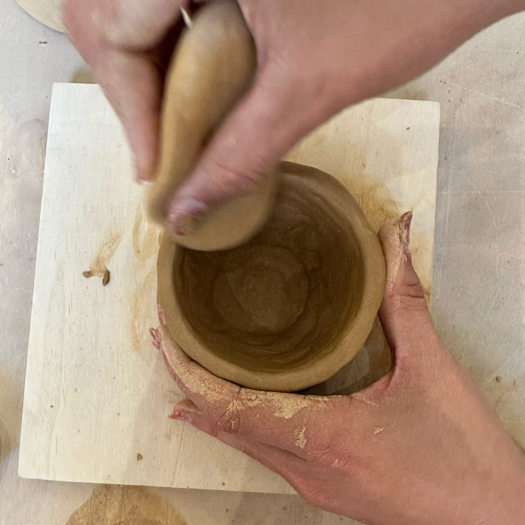 Deux mains de femme sculptant une tasse en argile, illustrant l’activité thérapeutique de la poterie.